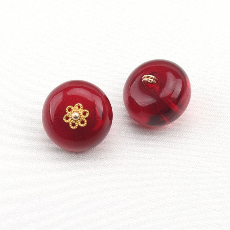 Two dark red resin round buttons with gold floral studs and metal shanks on top