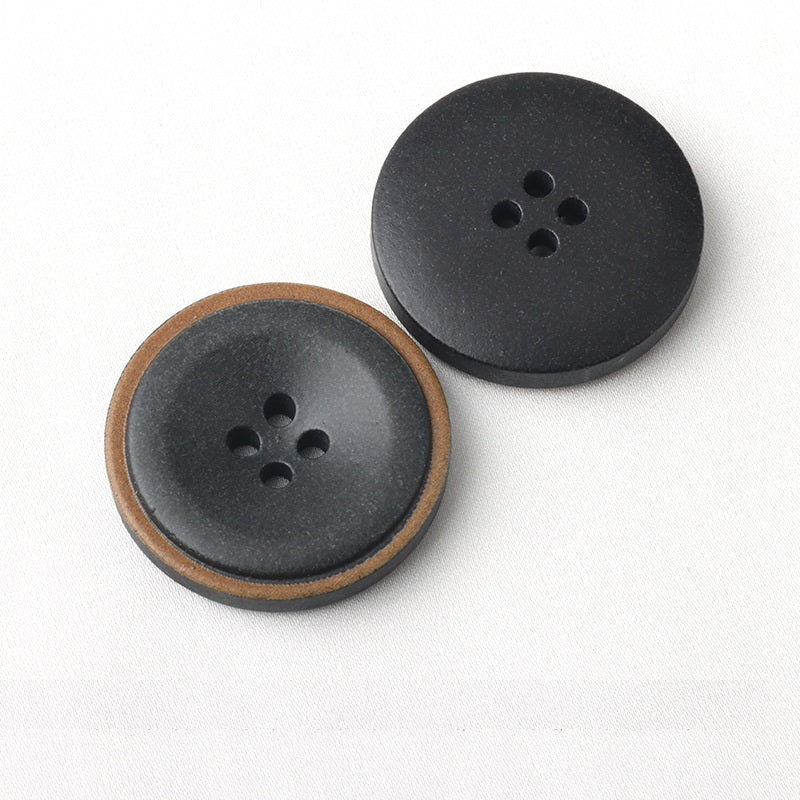 Two dark four-hole coat buttons with burnt edge trim