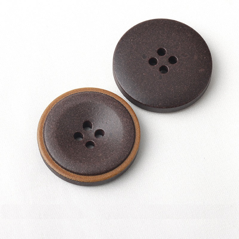Dark coat buttons with burnt edges and four-hole shank
