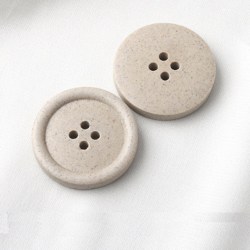 Two round four-hole buttons, frosted beige resin, front view