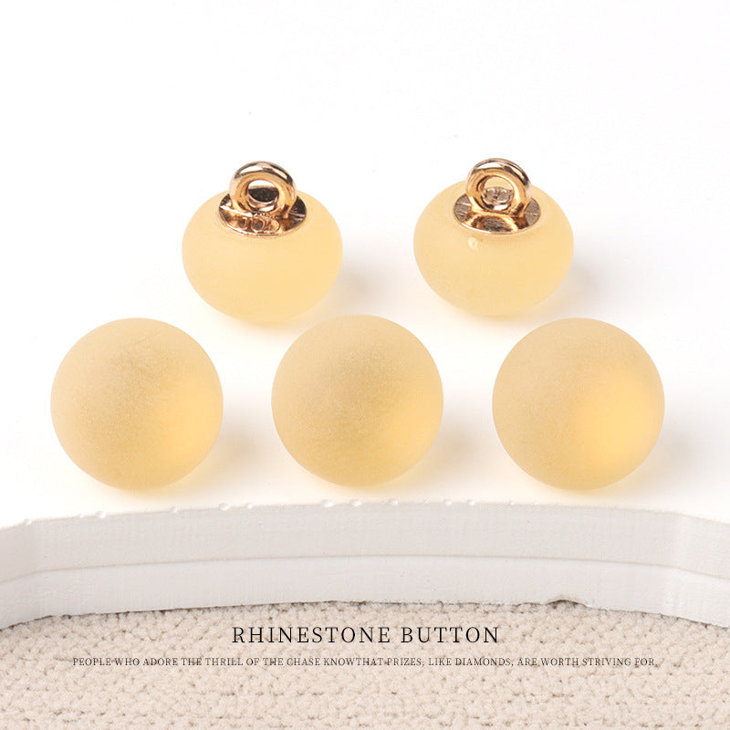 Round matte resin buttons in pale yellow/cream with metal shank—small size.