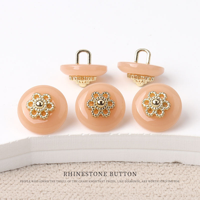 Round resin shank buttons, peach finish with gold floral rhinestone centers, shank backs shown