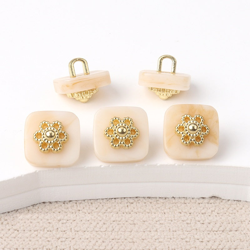 Square resin buttons with metal shanks, ornate silver center; beige/cream.