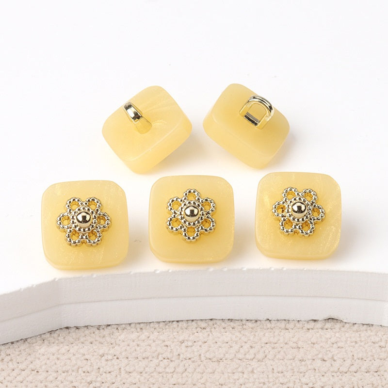 Square resin buttons with metal shanks, ornate silver center; yellow.