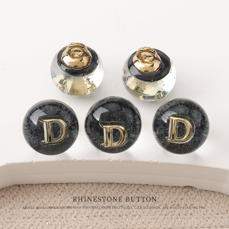 Dunkle Harzknöpfe 10 mm mit goldenen Metallbügeln, Buchstabe D