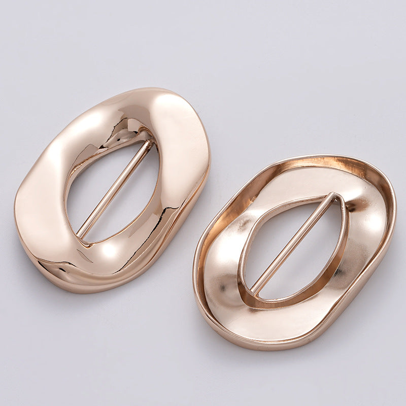 Set of 2 irregular rose-gold decorative buckles, angled top view for coats/swimsuits