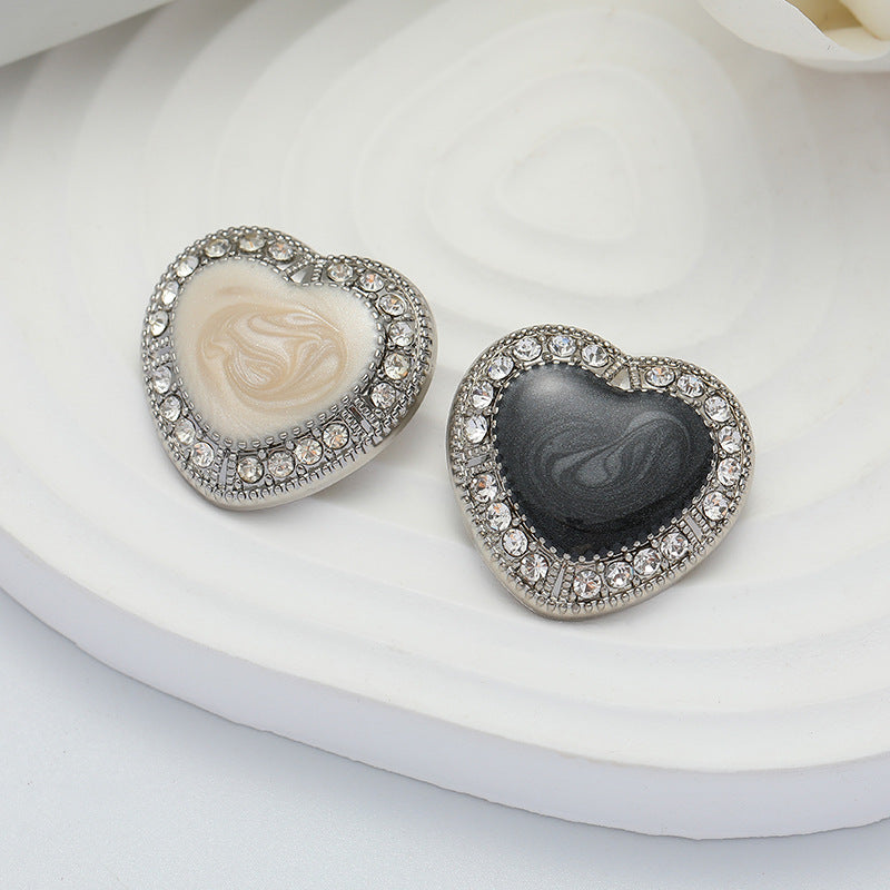 Heart-shaped metal buttons with black and white oiled centers and jeweled silver rim