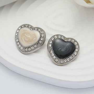 Heart-shaped metal buttons with black and white oiled centers and jeweled silver rim