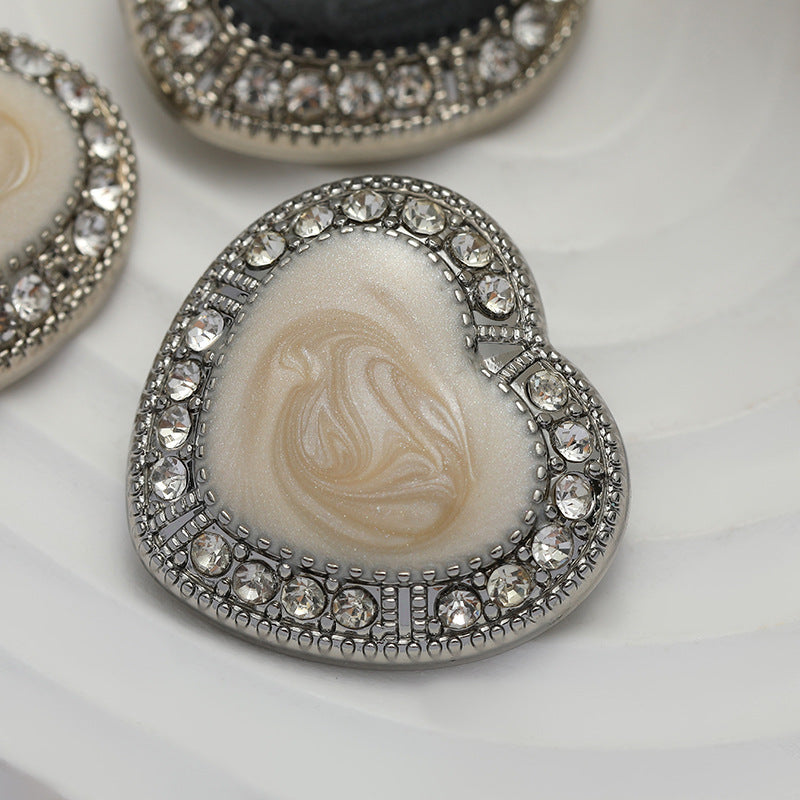 Heart-shaped white oiled metal button with crystal-like rhinestone border
