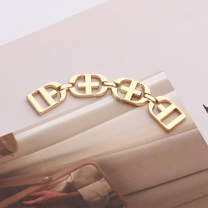 Gold-toned decorative chain buckle with letter-style link panels, clasp ends for clothing