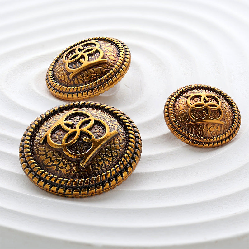 Drei runde Metallknöpfe mit goldfarbener Doppelkreis-Ornamentik und geripptem Rand