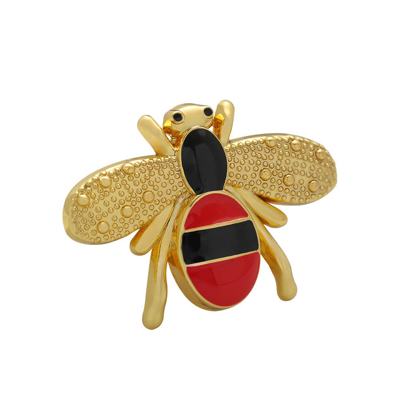 Gold cartoon bee brooch with red-and-black enamel body and textured wings.