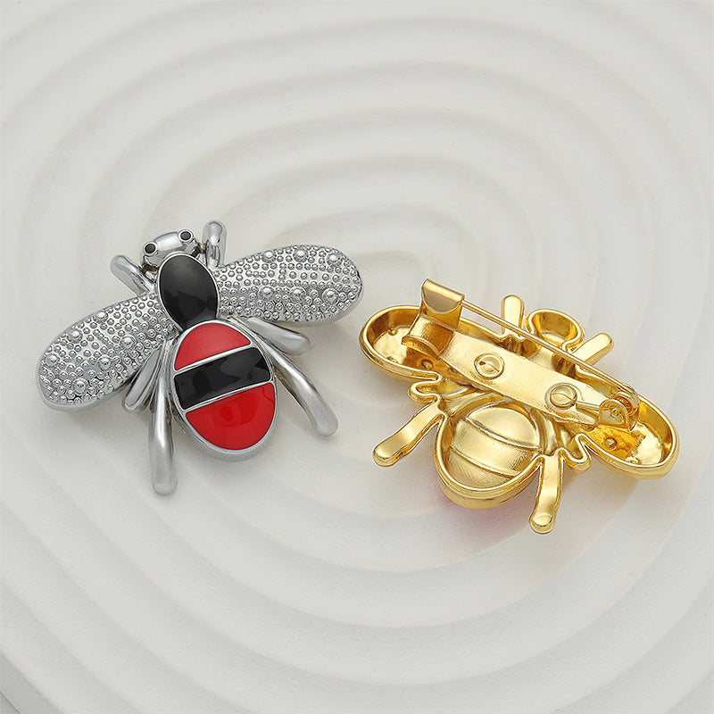 Silver and gold bee brooches with pin backs visible; red-and-black enamel.
