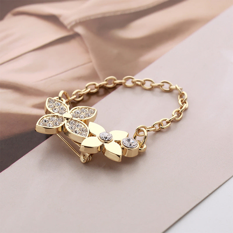 Gold-tone flower petal alloy brooch with rhinestone centers and oval crystal links