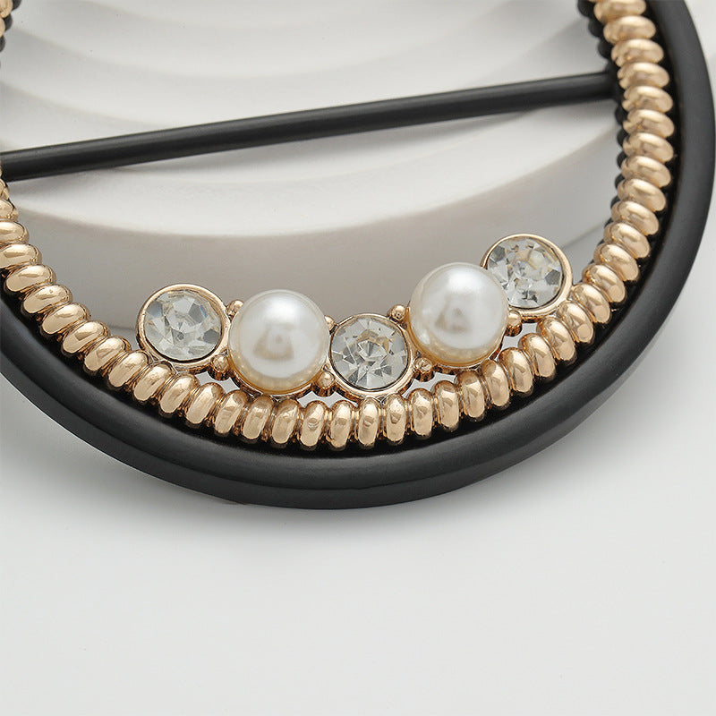 Close-up of round buckle: gold beads with pearl centers and crystal-look stones