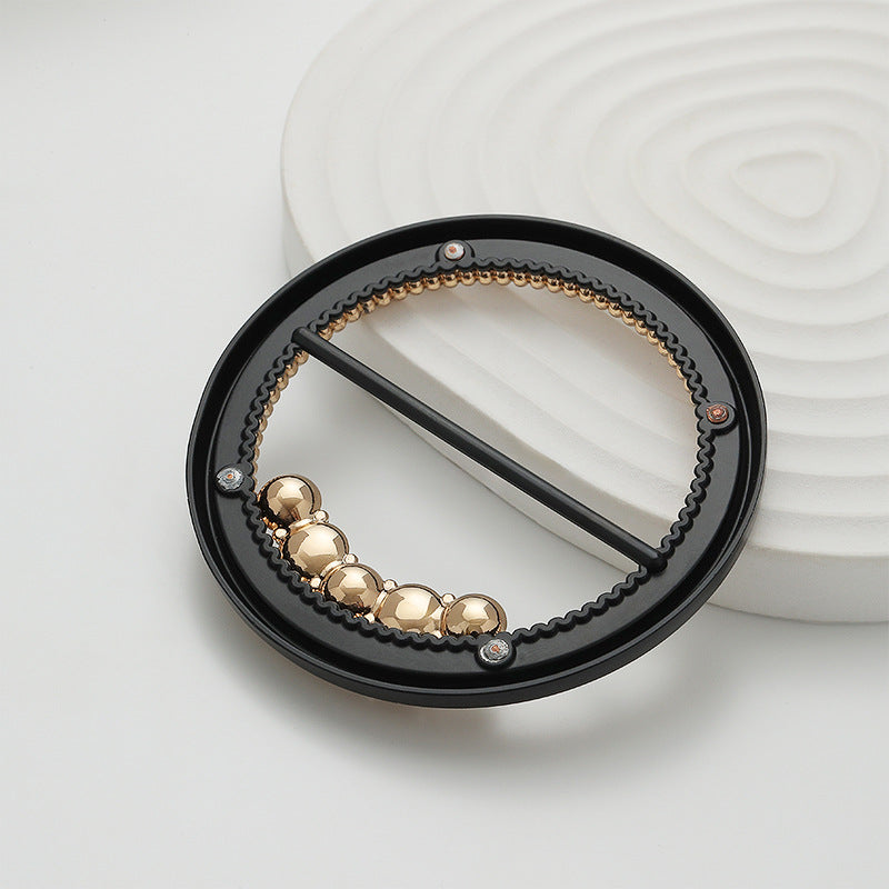 Round buckle with black base, gold bead trim, pearl and rhinestone drop details