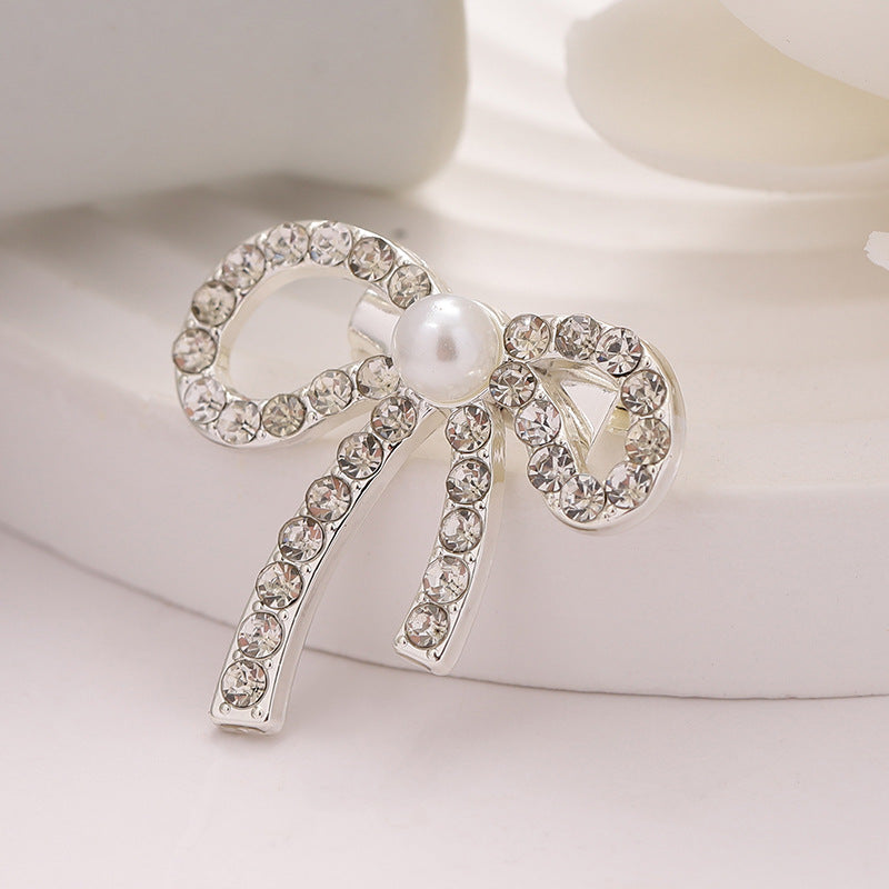 Bowknot waist cinching pin with clear rhinestones and round pearl centerpiece
