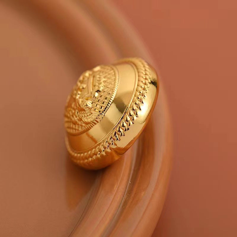 Gold metal button side view with engraved rim and textured edge detail