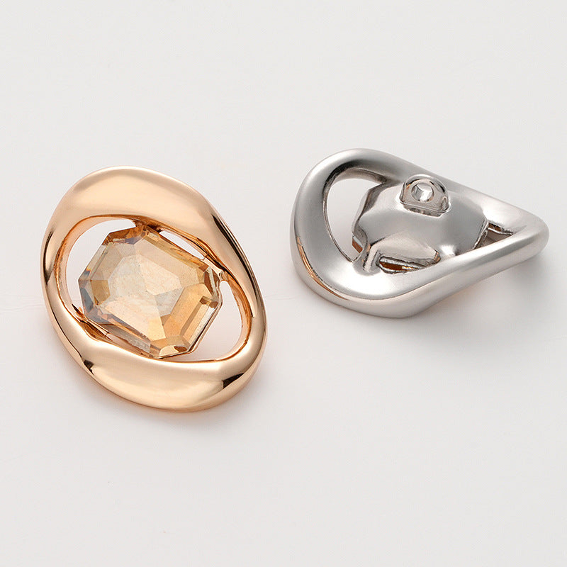 Two faceted crystal buttons: gold frame with light orange stone, silver with dark stone