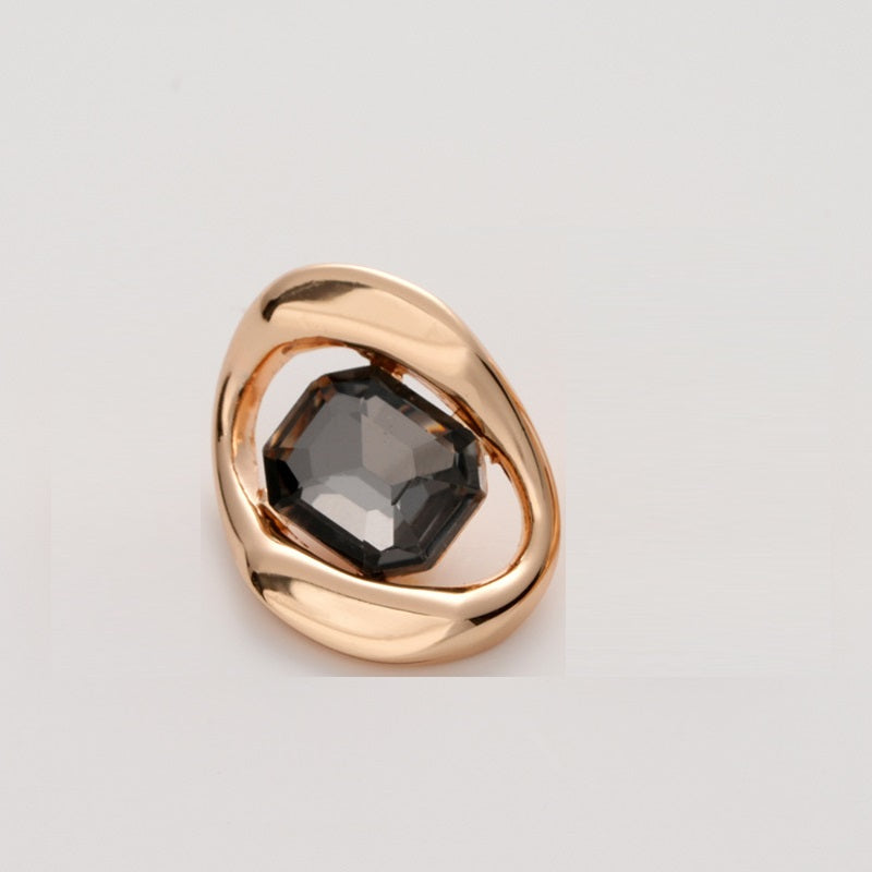 Gold-tone metal button with black faceted crystal, square irregular geometric setting