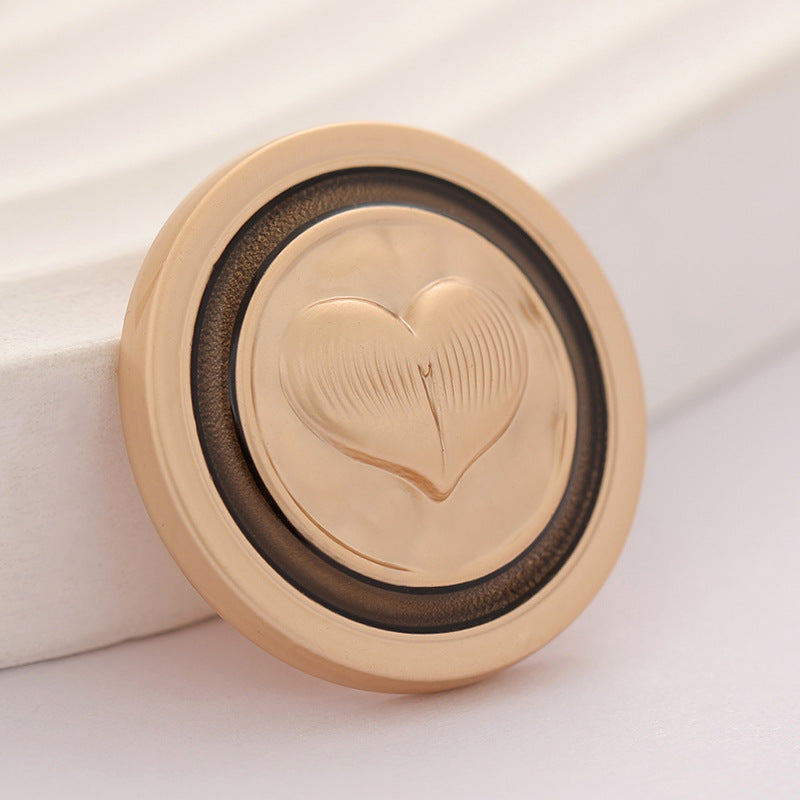 Gold-tone round metal coat button with embossed heart pattern