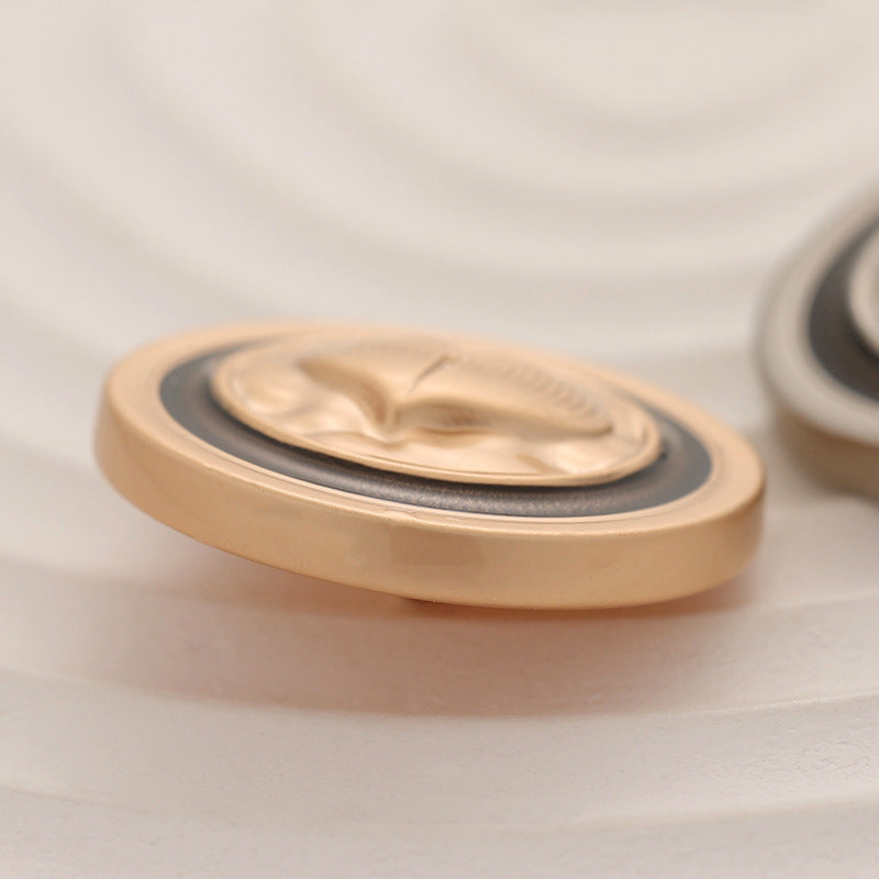 Gold-tone round coat button, close-up of heart-embossed face