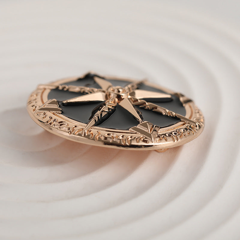 Side angle of gold-tone metal brooch: black star enamel with decorative border