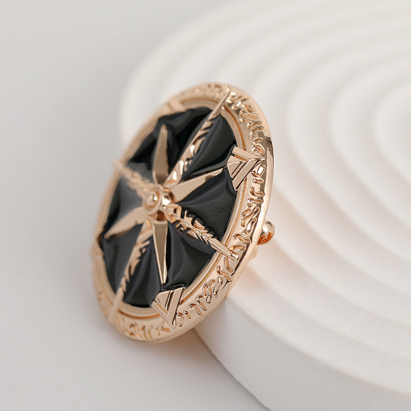 Rolled side view of gold-tone eight-point star brooch with black enamel center