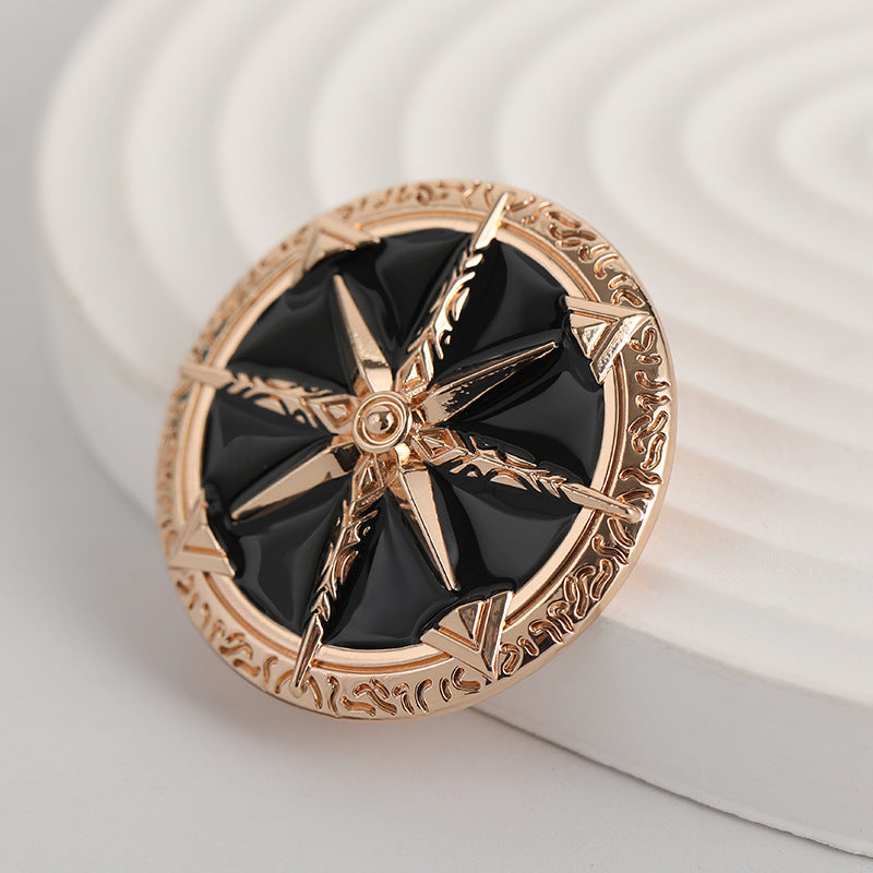 Front view of gold-tone eight-point star metal brooch with black enamel and center ring