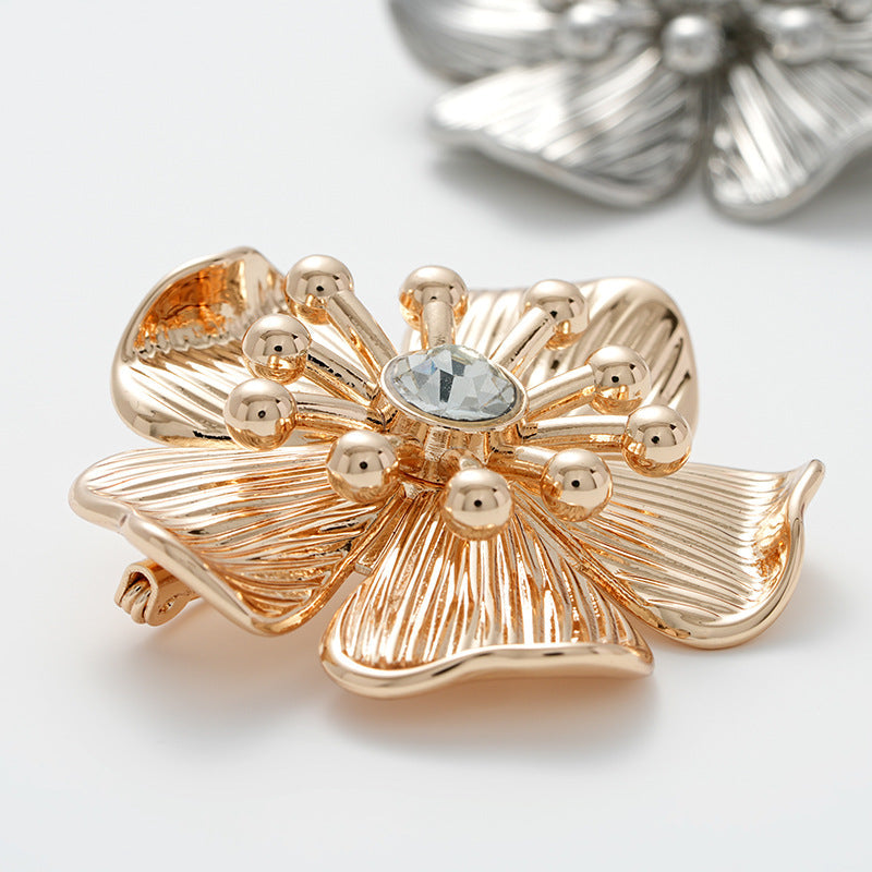 Gold flower brooch with central round rhinestone and pearl-like bead details