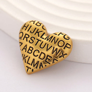 Gold heart-shaped vintage metal button with engraved alphabet letters, front view