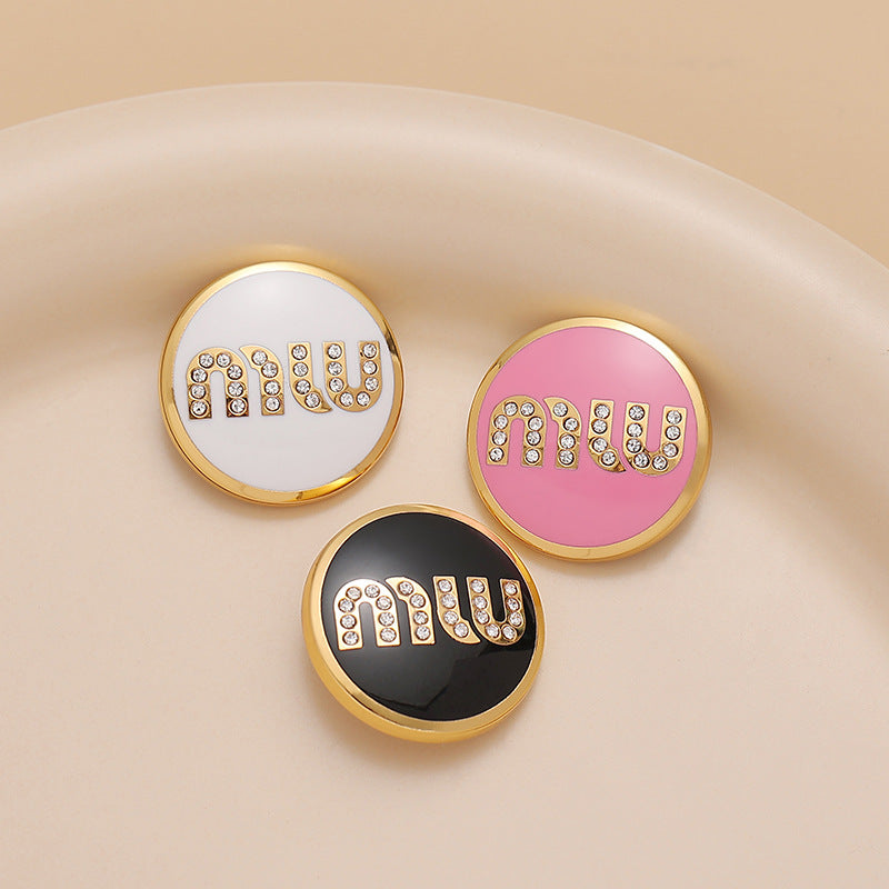 Round metal sewing buttons with MIU letters in white, black, and pink lacquer, rhinestones