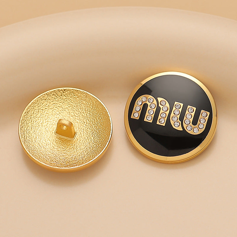 Round metal sewing button: black lacquer MIU with rhinestones; gold back visible