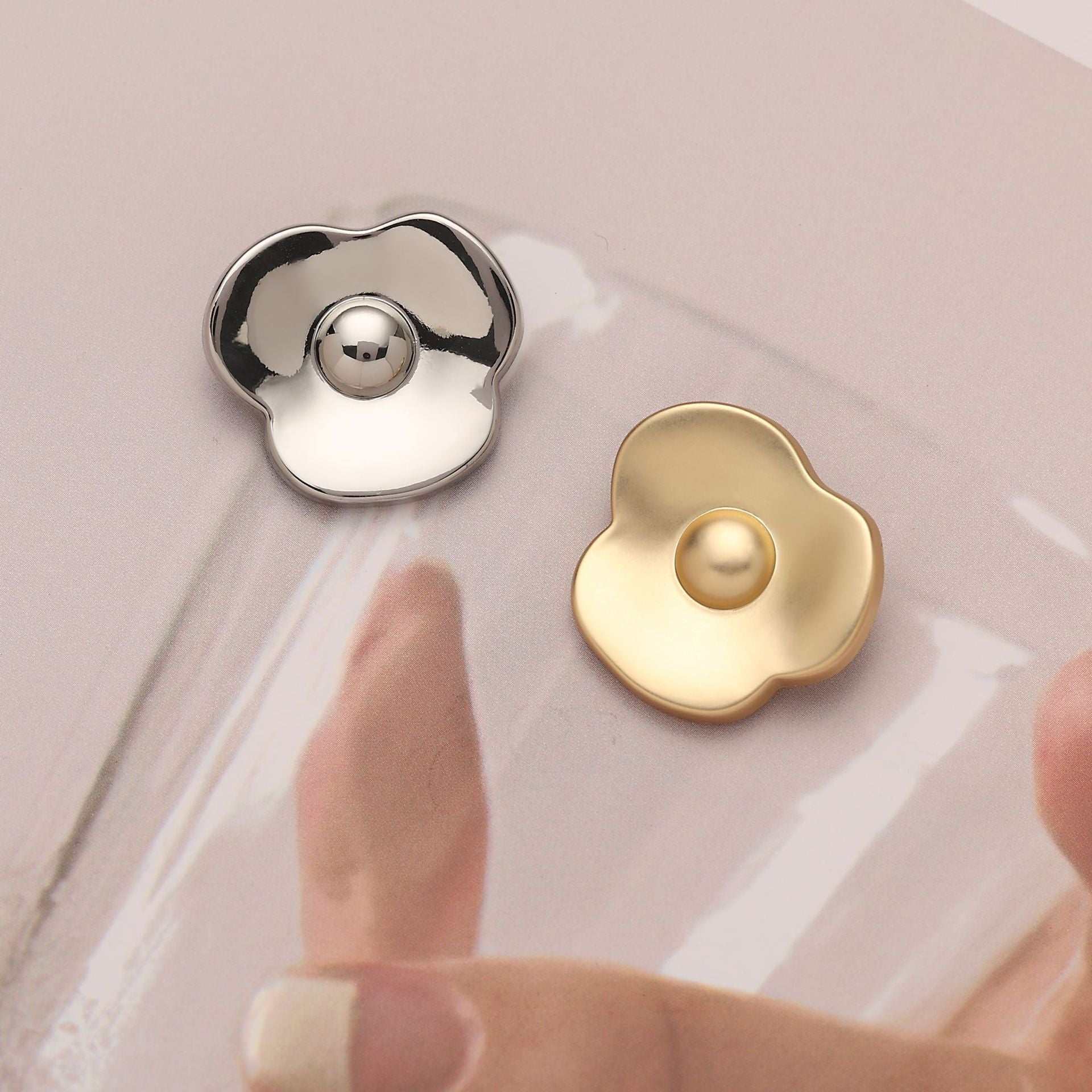 Kleeblatt-Metallknopf in Silber und Gold, jeweils mit rundem Knopfauge