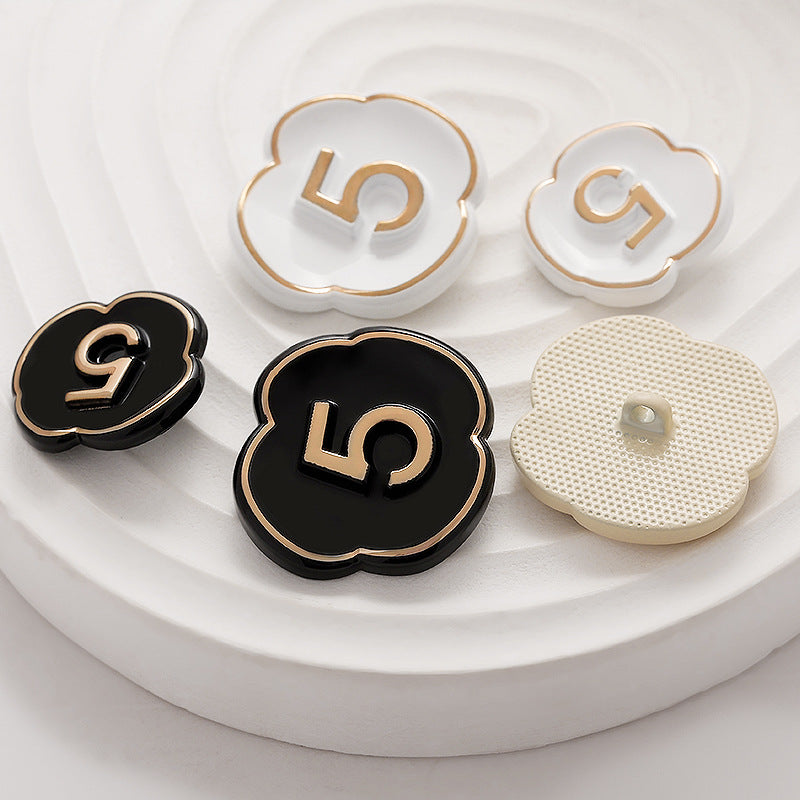 Number 5 lacquer buttons: black front with gold “5” and cream fabric-backed button.