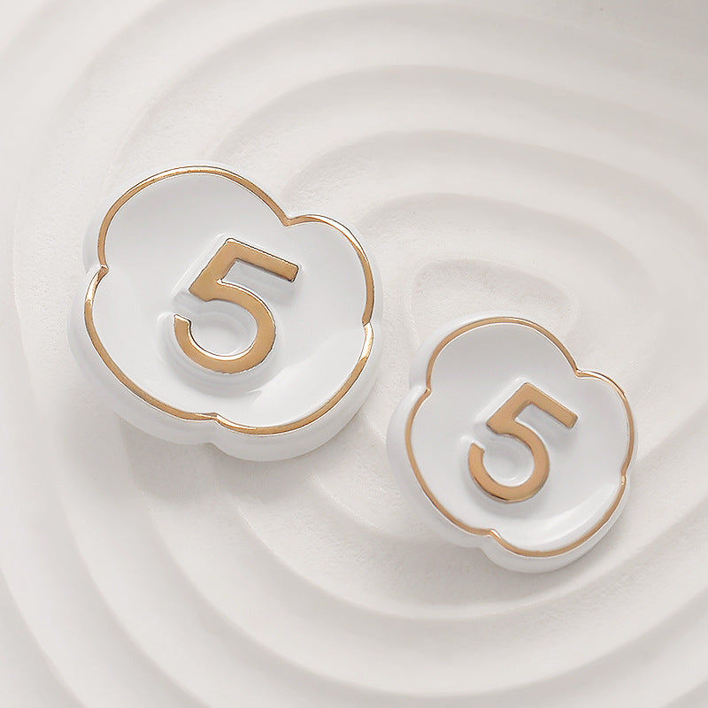White lacquer number 5 button with gold outline and raised “5” on flower-heart shape.