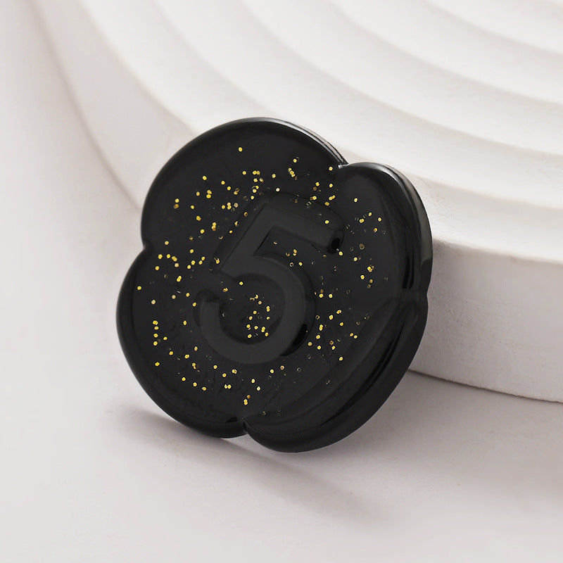 Pearlescent black number 5 lacquer button with gold speckles and raised “5”.