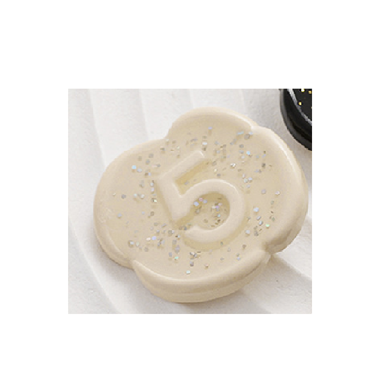 Pearlescent beige/white number 5 button with silver-gold speckle pattern and raised “5”.