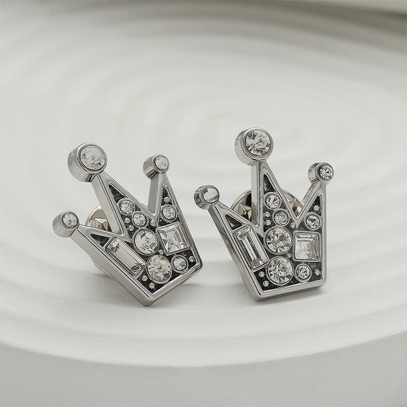 Silver crown badge brooch pair with diamond-style stones, angled view