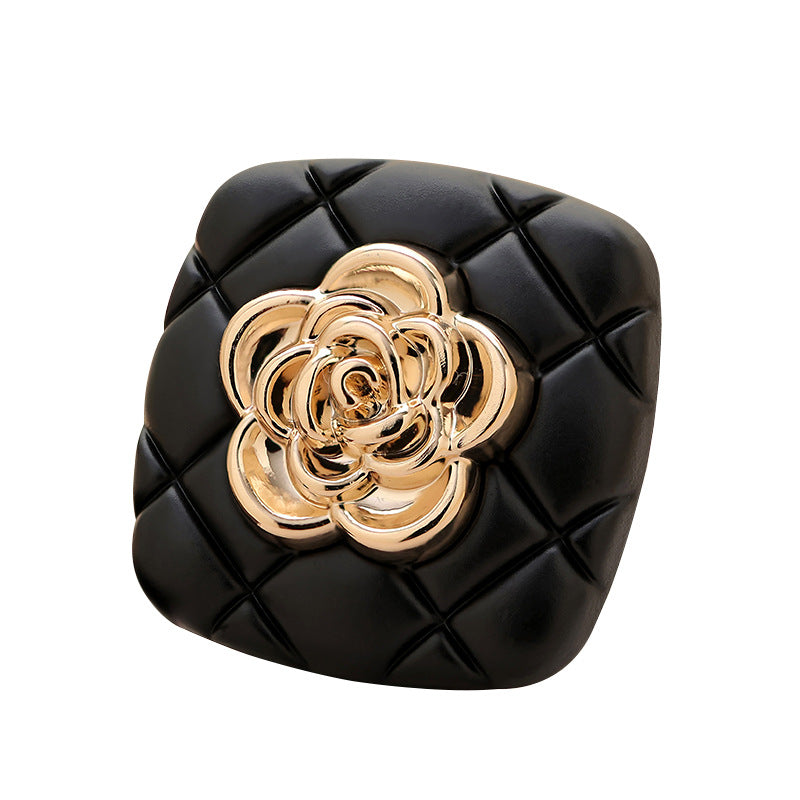 Black square metal button, gold camellia center on quilted grid, front view