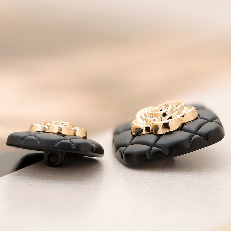 Black square metal button side view, gold camellia emblem on metal base