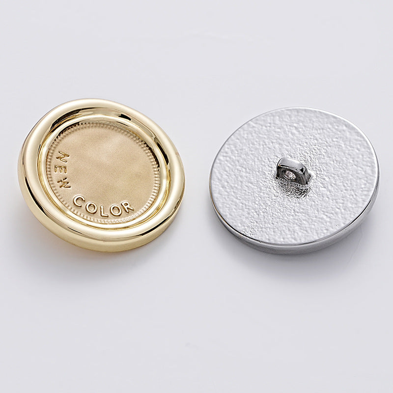 White-silver two-tone round metal sewing button with small metal loop handle.