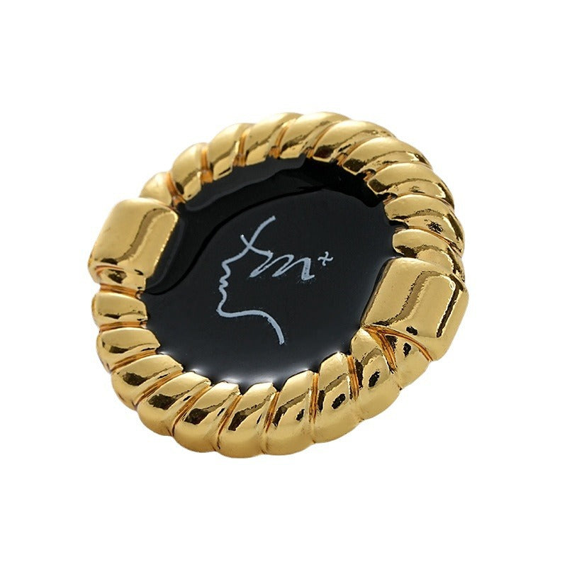 Gold metal button with black glossy face, rope edge, decorative pattern and shank