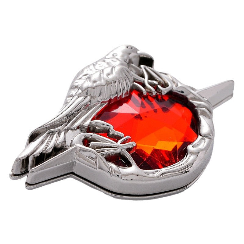 Close-up crow-shaped metal brooch with red faceted gem and silver wing details