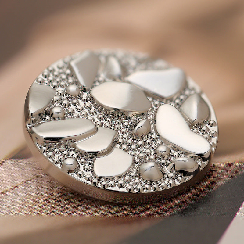Close-up of 30mm silver metal coat button showing pebble road pattern textures