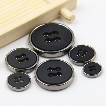 Round black plastic buttons with four-hole design and metal-look edge, mixed sizes