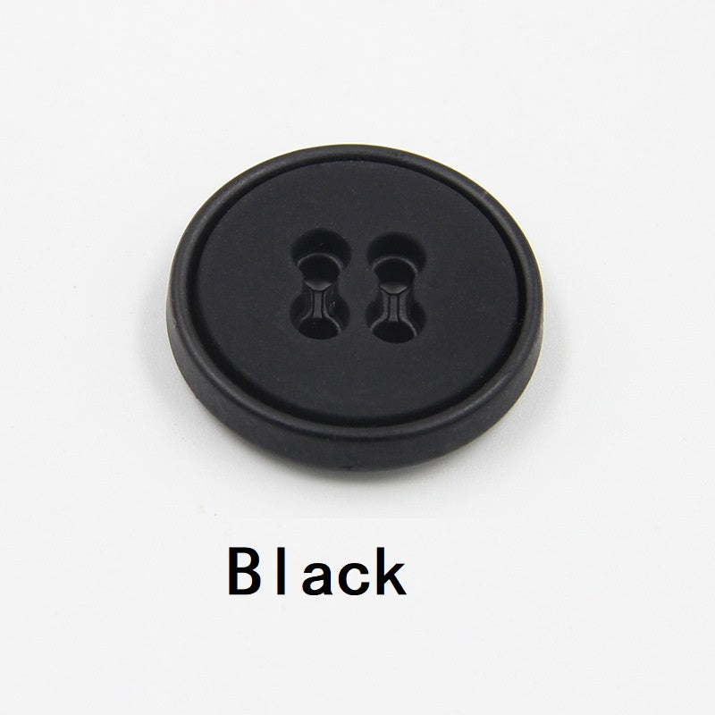 Round black plastic button with four-hole design and dark edge view