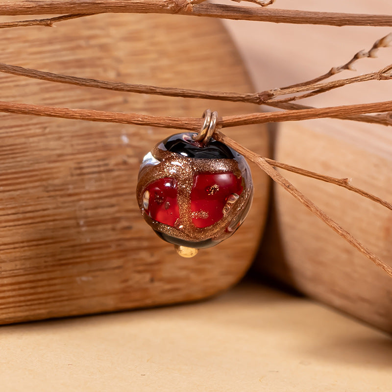 Red glazed apple-shaped bead button with gold glitter edge and metal loop shank