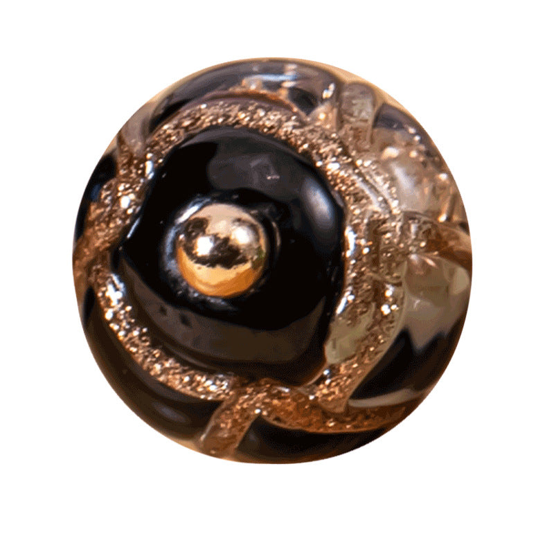 Close-up of glazed bead button with dark center and gold speckled rim; loop shank
