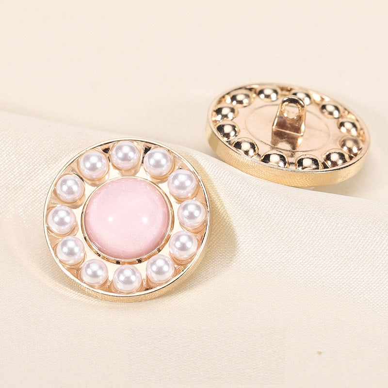 Round pearl resin button, pink center with gold rim; front view with back shank showing